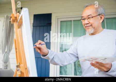 Un vieil homme asiatique peint en utilisant la couleur du pinceau et de l'huile sur la toile Banque D'Images