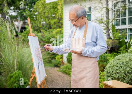 Un vieil homme asiatique peint en utilisant la couleur du pinceau et de l'huile sur la toile Banque D'Images