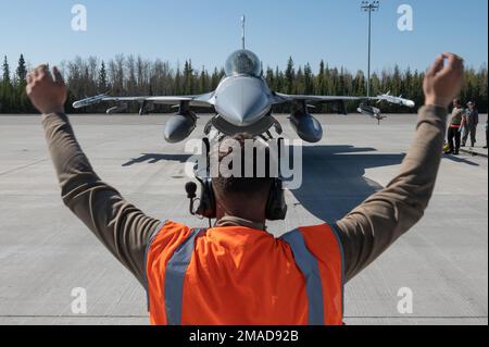 A ÉTATS-UNIS Un homme d'aviation affecté au 354th Escadron de maintenance d'aéronefs mobilise un américain Faucon de combat F-16 de la Force aérienne affecté à l'escadron 18th de l'agresseur en place pour le ravitaillement à ciel ouvert à la base aérienne d'Eielson, Alaska, 20 mai 2022. Le ravitaillement en carburant à ciel ouvert est une technique utilisée pour éliminer les temps d'arrêt et augmenter la fiabilité. Une fois qu'un avion atterrit et s'arrête; au lieu de mettre les moteurs hors tension, l'équipage maintient un moteur en marche pendant que l'avion est ravitaillé. (É.-U. Photo de la Force aérienne) Banque D'Images