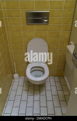 Cuvette de toilette en céramique près du mur jaune, toilettes publiques dans un établissement officiel, cuvette de toilette, toilettes, WC Banque D'Images