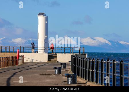 Ayr, Royaume-Uni. 19th janvier 2023. Après de basses températures et une chute de neige d'hiver, les gens prennent le point de vue au phare du port d'Ayr pour profiter de la vue sur le Firth de Clyde jusqu'aux collines enneigées de l'île d'Arran et du sommet de Goatfell. Crédit : Findlay/Alay Live News Banque D'Images