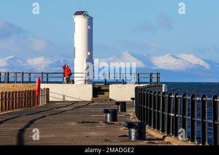 Ayr, Royaume-Uni. 19th janvier 2023. Après de basses températures et une chute de neige d'hiver, les gens prennent le point de vue au phare du port d'Ayr pour profiter de la vue sur le Firth de Clyde jusqu'aux collines enneigées de l'île d'Arran et du sommet de Goatfell. Crédit : Findlay/Alay Live News Banque D'Images