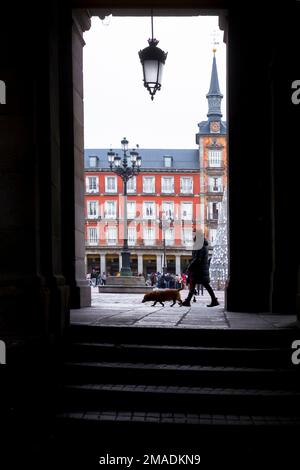 Vue silhouette d'une femme marchant son chien près des arches de la Plaza Mayor, Madrid Espagne Banque D'Images