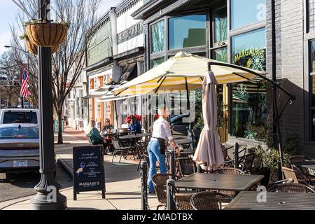 PINEVILLE, NC, USA-15 JANVIER 2023 : vue sur le trottoir passant par Margaux's et Christie's on main, avec des clients aux tables de trottoir et une serveuse à la main Banque D'Images