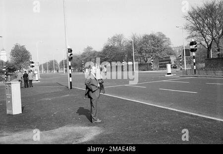 Fin 1950s, historique, un homme debout à côté de ce nouveau feu de circulation à un carrefour sur la route Wilmslow Rd (A34) près de Parrs Wood et East Didsbury, Greater Manchester, Angleterre, Royaume-Uni. Une artère très fréquentée, la route, la A34, est une route de circulation importante vers le centre-ville de Manchester. Banque D'Images