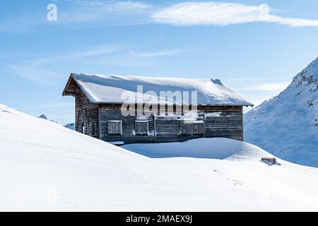 Détail d'une cabine en bois dans les montagnes pendant l'hiver couverte de neige fraîche par une journée ensoleillée en Suisse. Banque D'Images