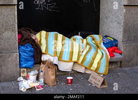 Barcelone, Espagne, 12 janvier 2019 : un homme sans domicile se fait dorer sur le sol dans un chemin public avec un vieux chapeau devant pour un don d'argent Banque D'Images