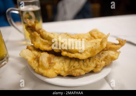 Assiette de poisson frit doré servie avec de la bière dans un restaurant italien traditionnel. Banque D'Images