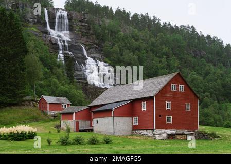 Tvindefossen est une cascade située près de Voss, en Norvège. Maison en bois scandinave traditionnelle de couleur rouge Banque D'Images