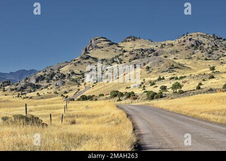 L'Ouest américain se présente avec une courbe montante de route de campagne, symbole de la Wanderlust décontractée accentuée par les collines du Montana, États-Unis Banque D'Images