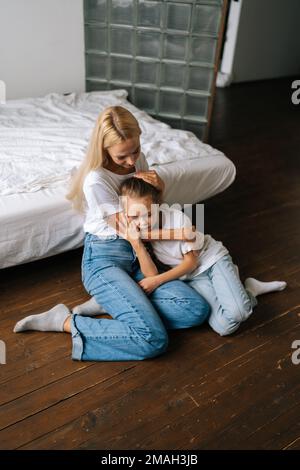 Portrait vertical de la jeune mère bienveillante réconfortante offense triste petite fille montrant l'amour et le soin, exprimant le soutien, embrassant, caressant Banque D'Images