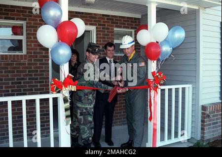 Brigadier général de l'USAF David L. Johnson (à droite), commandant de l'escadre du transport aérien 43rd, M. Locke McKnight (au centre), vice-président de la McKnight Construction Company, Et le lieutenant-colonel David Bender de l'armée américaine, le corps des ingénieurs de l'armée américaine, participent à la cérémonie de découpe du ruban pour le nouveau quartier résidentiel enrôlé par les jeunes, situé à la base aérienne de Pope, en Caroline du Nord. Mme Linda Poore, Directrice du Bureau de gestion du logement de l'AFB du Pape, regarde depuis la porte de la maison nouvellement achevée. Base: Pope Air Force base Etat: Caroline du Nord (NC) pays: Etats-Unis d'Amérique (USA) Banque D'Images