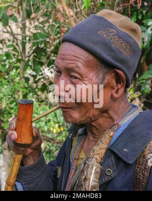 Raga, Arunachal Pradesh, Inde - 02 20 2013 : gros plan portrait en plein air de l'ancien homme de tribu Nyishi fumant le tube traditionnel de bambou sur fond naturel Banque D'Images