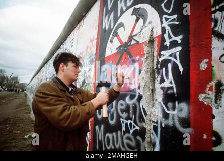 Un homme d'Allemagne de l'Ouest utilise un marteau et un burin pour couper un morceau du mur de Berlin comme souvenir. Une partie du mur a déjà été démolie à la Potsdamer Platz. Base: Berlin pays: Allemagne / Allemagne (DEU) Banque D'Images