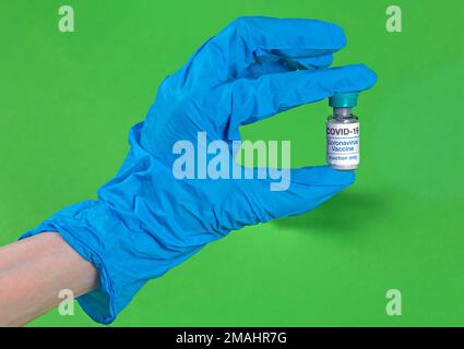 Main dans un gant de latex contenant un flacon en verre de vaccin contre le coronavirus Banque D'Images
