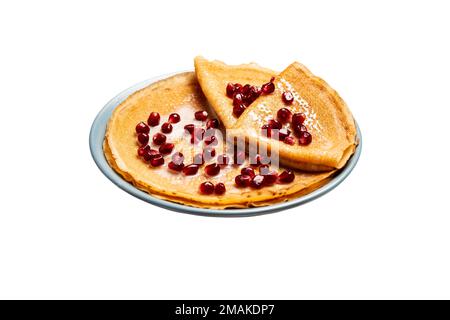 Les crêpes fines avec de la grenade et du lait condensé reposent sur une assiette sur un fond isolé Banque D'Images