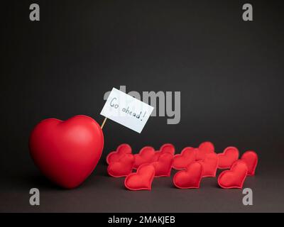 Grand coeur rouge mène beaucoup de petits coeurs comme Armée d'amour ou soldats d'amour, copier l'espace. Concept d'amorosité, Journée des amoureux, Saint-Valentin Banque D'Images