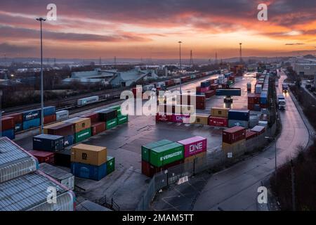 Vue aérienne du terminal de conteneurs intermodal Freightliner à Leeds au coucher du soleil avec des machines lourdes chargeant des conteneurs sur les transports routiers et ferroviaires Banque D'Images