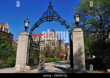 Chicago, Illinois, États-Unis. Un cycliste solitaire passe par Cobb Gate à l'extrémité sud de Hull court, sur le pittoresque campus de l'Université de Chicago. Banque D'Images