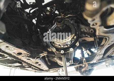 Dépose et installation d'un nouveau kit d'embrayage pour une voiture dans un atelier de réparation automobile. Photo de haute qualité Banque D'Images