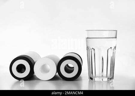 Bannière de trois cartouches pour filtre à eau avec verre d'eau propre isolé sur fond blanc. Installation de RO, eau d'osmose inverse Banque D'Images