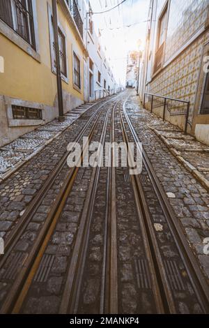 Une vue verticale grand angle d'une voie de tramway au-dessus de la pierre pavée portugaise sur un petit quartier pittoresque de Lisbonne dans les tons de jaune sur la W Banque D'Images