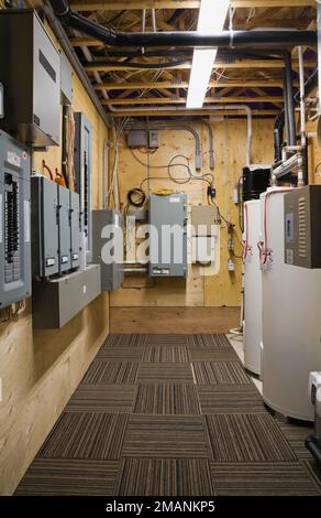 Panneaux d'électricité et réservoirs de chauffe-eau dans la salle de service au sous-sol à l'intérieur de la luxueuse maison scandinave en bois et en rondins. Banque D'Images