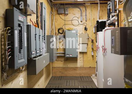 Panneaux d'électricité et réservoirs de chauffe-eau dans la salle de service au sous-sol à l'intérieur de la luxueuse maison scandinave en bois et en rondins. Banque D'Images