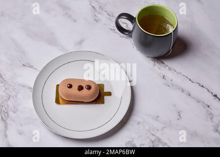 un sandwich sur une assiette avec une tasse de thé en arrière-plan et une tasse de café à côté Banque D'Images