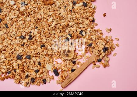 avoine sur une surface rose avec une cuillère en bois à l'arrière-plan et une image de bleuets, d'amandes et de noix Banque D'Images