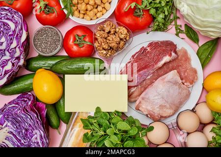 certains aliments qui sont sur une surface rose avec des légumes, des œufs, des citrons, des tomates et d'autres aliments Banque D'Images