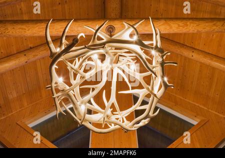 Lustre illuminé de bois de cerf au-dessus du salon à l'intérieur de la maison en rondins de style scandinave. Banque D'Images