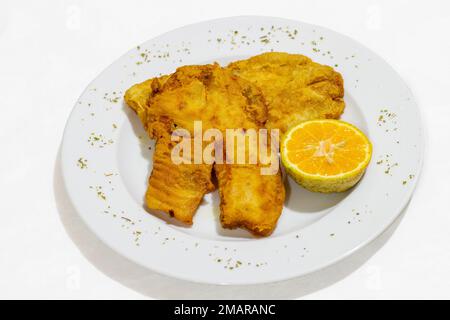 filet de poisson frit sur une assiette sur fond blanc Banque D'Images