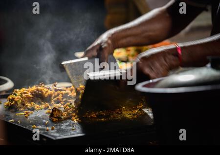 Les mains du fournisseur de kottu roti, qui fait du kottu sur une plaque de gril en acier chaud Banque D'Images