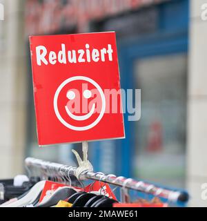 Signe avec l'inscription allemande Reduziert, indiquant les vêtements sur offre spéciale devant un magasin à Magdebourg en Allemagne. Traduction : réduite Banque D'Images