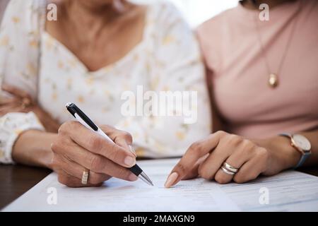 Quelques pas plus près de la liberté financière. une femme qui fait des formalités administratives avec sa mère âgée à la maison. Banque D'Images