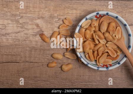 Arachides dans une tasse sur fond de bois Banque D'Images