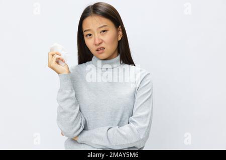 Triste femme asiatique tenant la main avec mouchoir et toussant la grippe et le froid, nez étouffant maladie virale asthme et allergies covid, fond blanc Banque D'Images