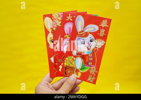 Enveloppes rouges à thème avec lapin, mots de bénédiction chinois sur fond jaune pour le nouvel an lunaire chinois. Bonjour 2023 année de lapin. Décoration Imlek. Banque D'Images