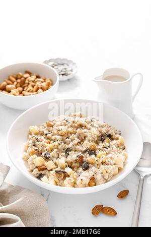 Bol à flocons d'avoine. Bouillie d'avoine aux noix, aux pommes, aux graines de chia et aux graines de citrouille pour un petit déjeuner ou un déjeuner sain. Alimentation végétalienne saine, régime alimentaire Banque D'Images