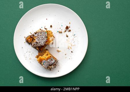 Restes de desserts sucrés sur une assiette blanche en céramique avec nappe verte Banque D'Images