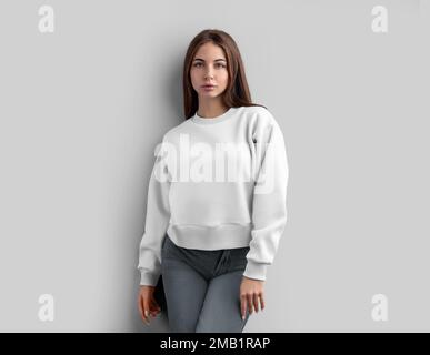 Modèle d'un petit-shirt blanc sur une fille, regardant droit devant, un sweat-shirt est isolé sur l'arrière-plan, vue de face. Mockup vêtements pour Femme, caillot Banque D'Images