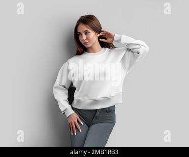 Une maquette d'un petit-shirt blanc sur une fille, redresse ses cheveux, un sweat-shirt avec un endroit pour le design, la marque, le devant. Modèle de vêtements pour femmes, vêtements Banque D'Images