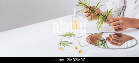 Cannabis en main. Pilules pharmaceutiques, capsules sur une table blanche. Concept production de mélatonine et restauration de la routine de sommeil. feuilles, huile cbd Banque D'Images