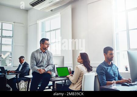 Travail d'équipe, écran vert pour ordinateur portable et professionnels en conversation, discussion ou conversation au bureau. Collaboration, maquette et employés, homme et femme Banque D'Images