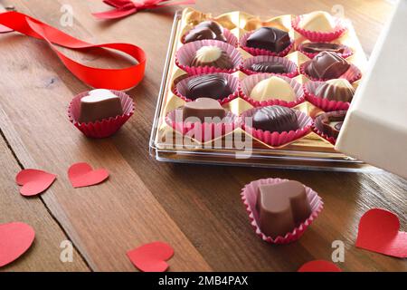 Présentation d'un assortiment de chocolats avec des découpes en forme de cœur rouge sur une table en bois. Vue en hauteur. Banque D'Images