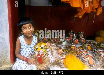 Une jeune fille posant avec un masque pulikali dans sa main à Thrissur ou Trichur, Kerala, Inde, Asie Banque D'Images