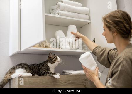 Femme mettant ou affichant soigneusement une serviette blanche enroulée propre en coton biologique. Banque D'Images