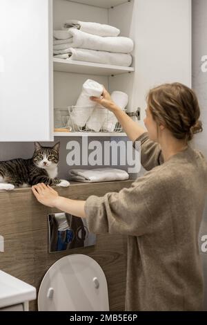 Femme mettant ou affichant soigneusement une serviette blanche enroulée propre en coton biologique. Banque D'Images