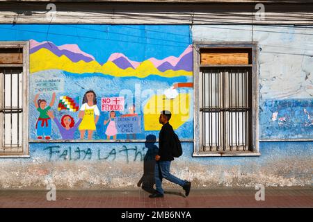 Homme marchant devant une murale sur le mur de l'école protestant contre la violence à l'égard des femmes et réclamant l'égalité des droits pour les femmes, Copiapo, Chili Banque D'Images